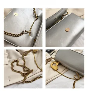 Detail view of silver matte leather bag with gold safety pin buckle and magnetic closure