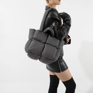 Dark grey quilted puffer tote bag with padded handles and wide shoulder strap shown on model