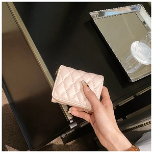 Detailed shot of a pink quilted mini coin purse with golden zipper in a lifestyle setting