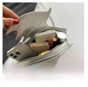 Internal capacity of silver bat wing crossbody bag showing phone and lipstick space