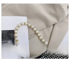 Dettaglio macro del manico di perle e degli strass argentati su una borsa nera elegante