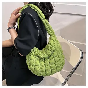 Detail der grünen gesteppten Cloud-Tasche mit breitem Trageriemen am Model im Anzug