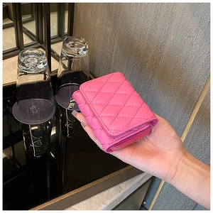 Close-up of a pink quilted accordion wallet with flip cover and metal zipper detail