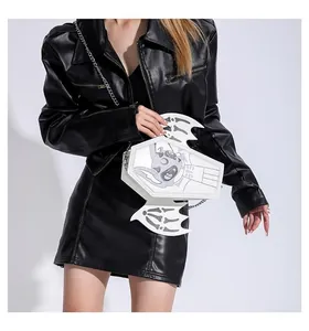 Detail of white coffin-shaped crossbody bag with bat wings on a black leather outfit