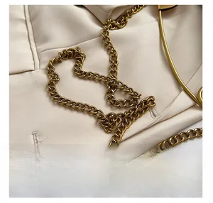 Macro detail of high-quality gold chain strap on textured beige shoulder handbag