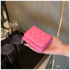 Close-up of bright pink quilted leather tri-fold wallet held in hand with metal zipper detail