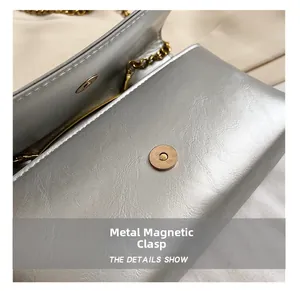 Macro view of gold magnetic closure on silver textured leather shoulder bag with chain