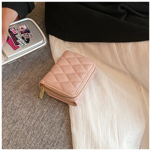 Detail of pink quilted card holder with gold zipper on a textured background