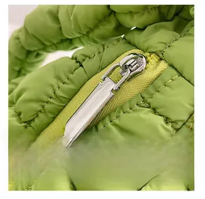 Detail of smooth silver zipper on green quilted puffer bag with precise stitching