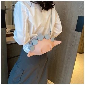 Detailed side view of a cute pink dinosaur crossbody bag worn by a model in a casual setting