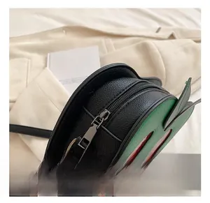 Detail of silver metal zipper and textured black and green leather on small underarm bag