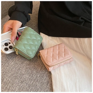 Close-up of quilted leather mini wallets in mint green and dusty pink with gold zippers