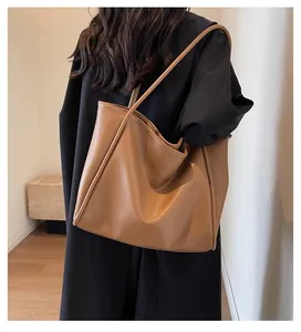 Close-up of large caramel tote bag with litchi texture and slender shoulder straps