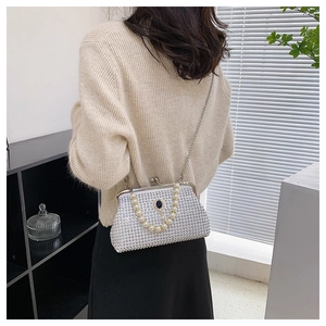Dettaglio borsa da sera in strass argento con manico di perle e chiusura a gemma blu