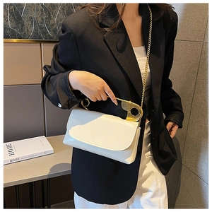 Detail of white leather shoulder bag featuring a unique gold safety pin metal handle