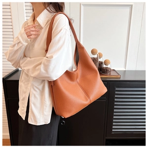Dettaglio della borsa tote color caramello con cucitura verticale sulla spalla del modello