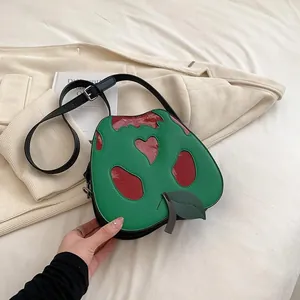 Detail of apple-shaped green shoulder bag with red heart patchwork and leather leaf detail