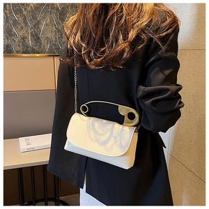 White minimalist square crossbody bag with oversized gold safety pin handle detail