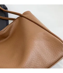 Detailed close-up of brown tote bag showing premium lychee texture and stitching