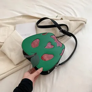 Detailed view of the creative green and purple apple-shaped crossbody bag with leaf detail