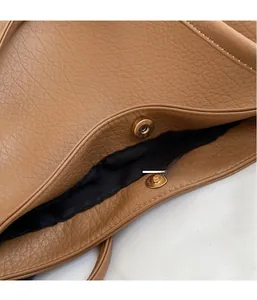 Macro view of hardware magnetic buckle on brown leather tote bag with fabric lining