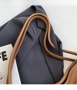 Close-up of thick leather handles and lychee grain texture on a caramel tote bag