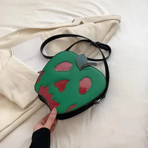 Detail of poisonous apple crossbody bag with skull pattern and green leaf zipper pull