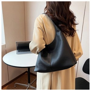 Dettaglio della borsa hobo nera in pelle martellata indossata da una modella in ufficio