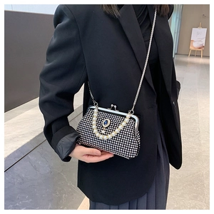 Dettaglio di borsa da sera nera con strass argento, gemma blu e manico di perle