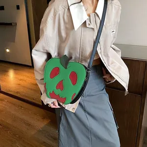 Detail view of the green apple-shaped bag with a red skull face on a fashion model