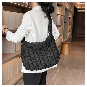 Detail of a large black quilted hobo cloud bag with a soft puffy texture and shoulder strap
