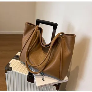 Macro view of textured brown leather tote bag with thick straps on a suitcase