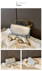 Macro shot of silver pleated leather texture and gold safety pin handle on shoulder bag