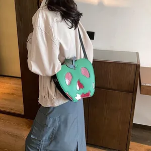 Detailed view of apple-shaped crossbody bag featuring a skull design and leaf detail