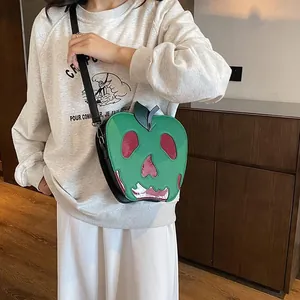 Close-up of green apple-shaped bag with red skull face detail and black strap