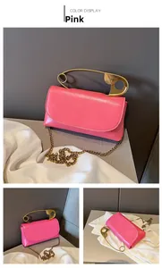 Pink glossy leather shoulder bag with unique golden safety pin handle and chain strap detail