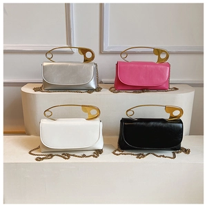 Detail view of colorful glossy square bags with unique gold safety pin handles and chains