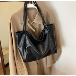Close-up of black litchi pattern tote bag with slender straps and textured leather finish