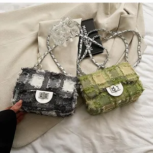 Detail of tweed quilted bags with metallic chain and fringe trim on fabric surface