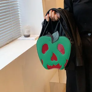 Detailed view of the green apple-shaped bag with a red skull face and leaf accent