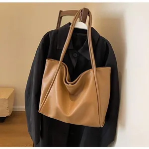 Close-up of the pebbled leather texture and reinforced shoulder strap on camel tote bag