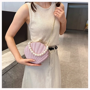 Detail of pink shell-shaped crossbody bag with pearl handle and glitter finish