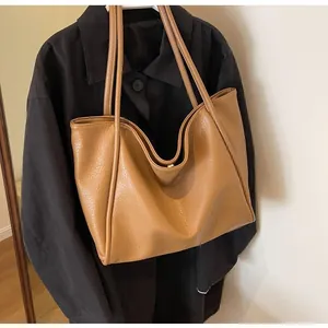 Detailed view of the brown litchi grain leather texture and magnetic buckle on tote bag
