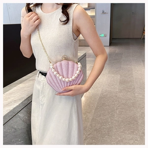Detail of pink shell crossbody bag with pearl handle and fine glitter texture