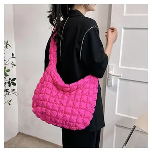 Quilted rose pink puffy tote bag with wide shoulder strap shown on a model