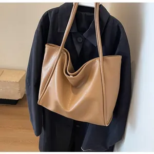 Detail of tan pebble-leather tote bag showing texture and magnetic clasp on shoulder strap