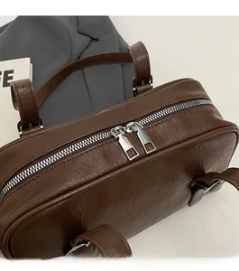 Gros plan sur les doubles fermetures éclair argentées d'un sac d'épaule marron foncé