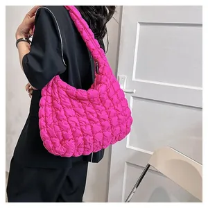 Detailed close-up of a hot pink quilted puffer shoulder bag with a puffy cloud texture