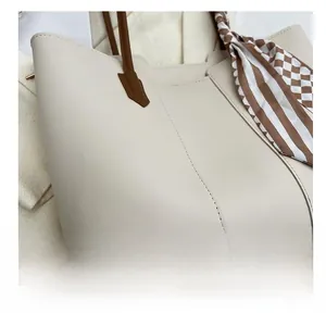 Close-up of fine stitching on a beige leather tote bag with a striped silk scarf detail