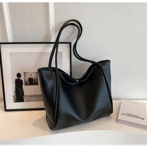Detailed close-up showing the lychee texture of the black faux leather tote bag